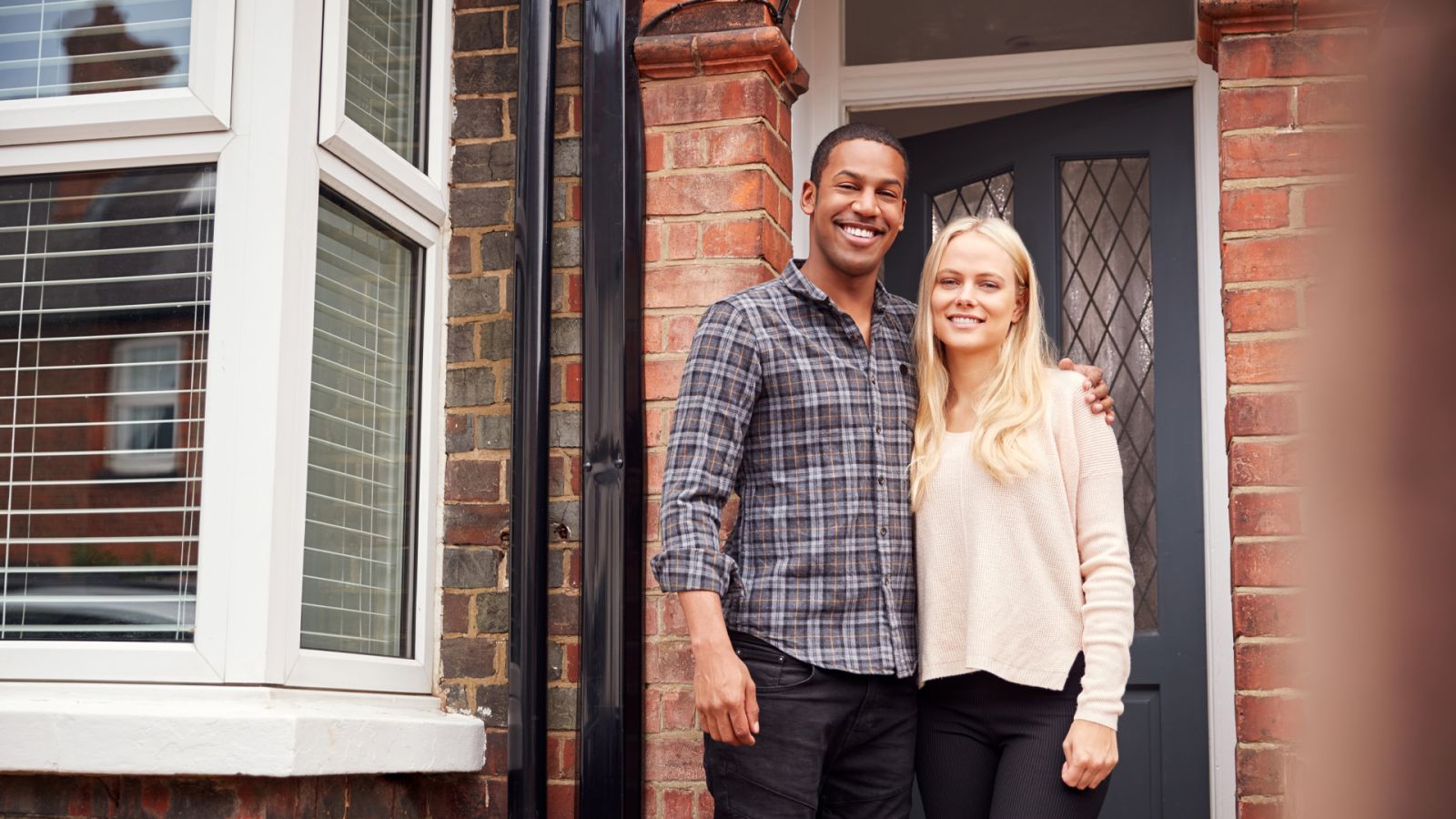 Two people standing outside the front door of a brick house